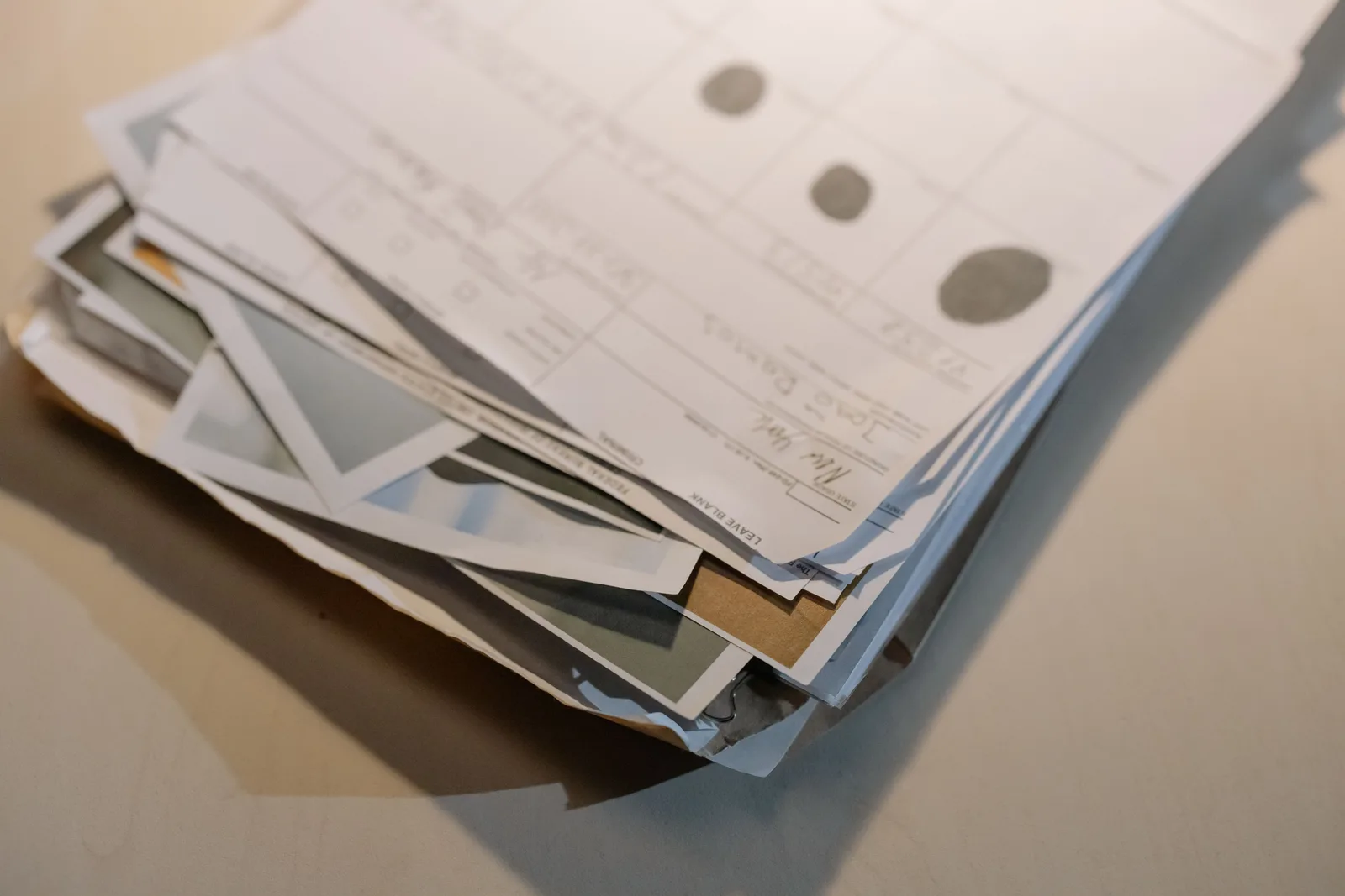 Close-up view of a stack of various papers and documents on a desk surface. Federal grant requirements for applicants