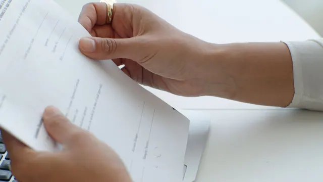 Close-up view of hands holding a document over a keyboard in an office. What the grants for women examples have in common