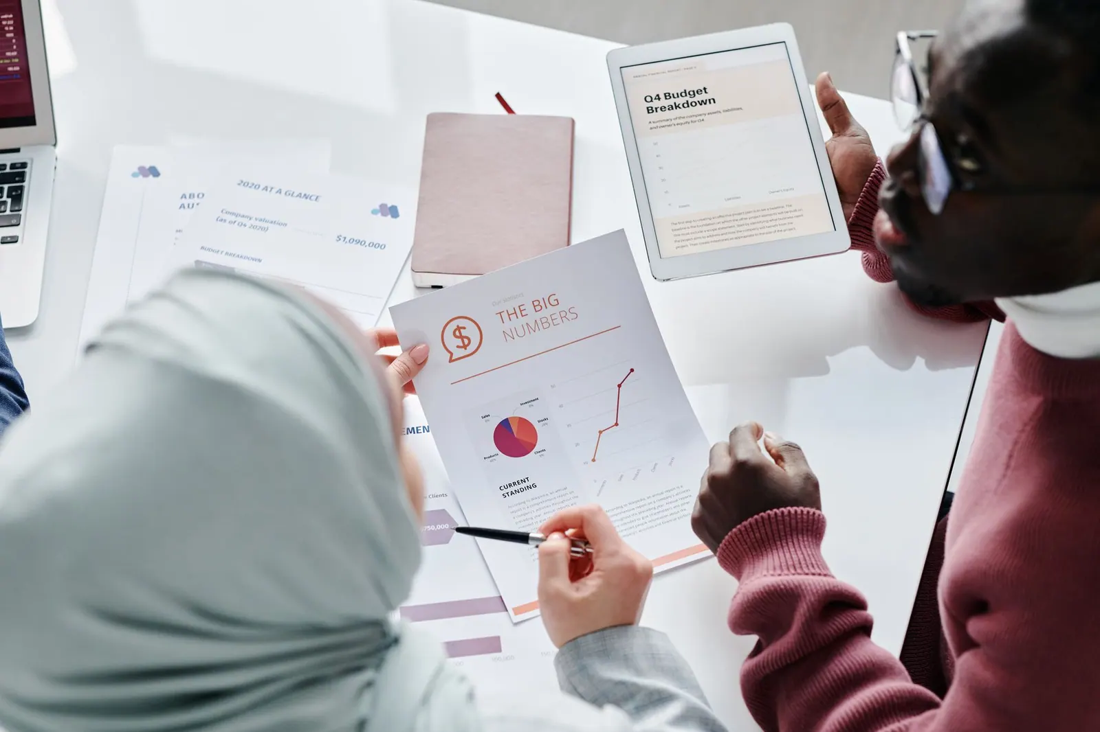 Two colleagues reviewing financial documents and graphs during an office meeting. Minority business grants review in plain terms, updated for 2027